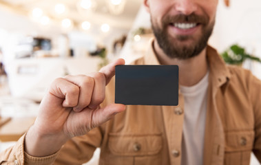 Young handsome bearded man holds bank card to pay online , business and finance concept