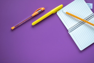 School supplies on purple background. Notebook open page. Workspace of student or office 