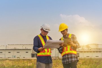 Supervisor holding blueprint talk with Foreman checking layout factory construction work place outdoor