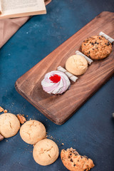 Vanilla meringue cake with butter and oatmeal cookies on a cutting board on a blue table