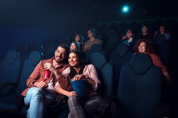 Group of cheerful people laughing while watching movie in cinema. - obrazy, fototapety, plakaty