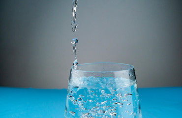 Splashes of water in a glass frozen in the form of unusual figures on a blue background.