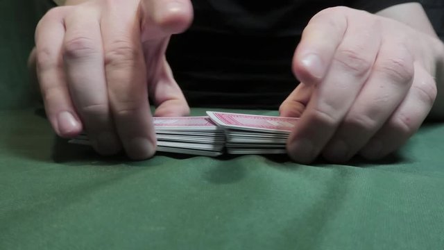 Riffle Shuffle. Male hand shuffling cards on green cloth. Close-up. Gambling. Games of chance