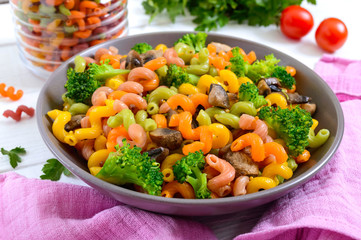 Cavatappi colored pasta with broccoli and mushrooms on a white wooden background. Pasta colorata. Pasta with vegetables