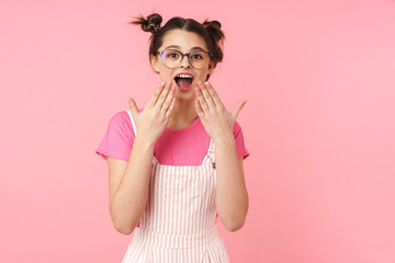 Excited lovely teenage girl standing isolated over pink