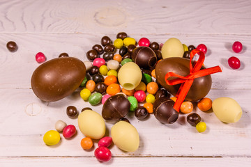 Naklejka na ściany i meble Chocolate easter eggs and multicolored candies on wooden table