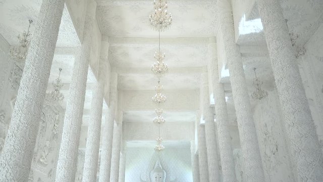 Tilt down revelation of the white Buddha satue inside the main prayer house at Wat Huay Pla Kung (Big Buddha), Thailand.