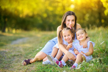 Happy family. Mom with daughters plays and rests in a beautiful park at sunset, family time.