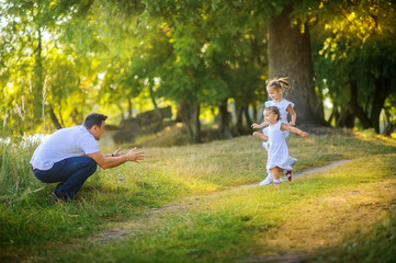 Happy family. Dad with daughters plays and rests in a beautiful park at sunset, family time.