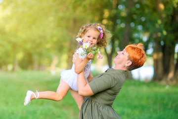 Happy family. Mom with her beloved daughter is resting in a beautiful park at sunset, family time.