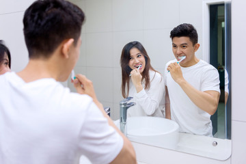 Happy couple cleaning their teeth together in bathroom