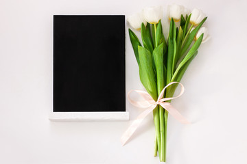 Black chalk board mockup with tulip flowers on white background. Blackboard menu with easel, spring sales. Copy space frame adding text content. Blank inscription template. Education training display.
