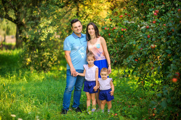 Fototapeta premium Happy family. A family walks in a beautiful apple orchard, family time.
