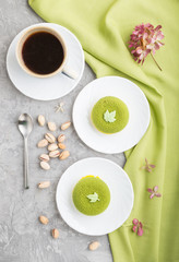 Green mousse cake with pistachio cream and a cup of coffee on a gray concrete background. top view, close up.