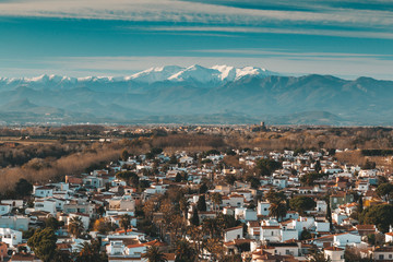 Traditional Spanish village cityscape with white houses in front of The Pyrenees with snow caps, travel destination for vacations, popular landmark