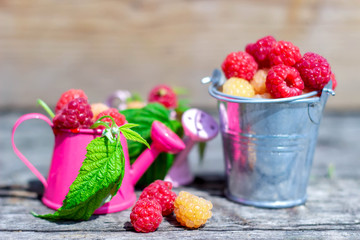 Ripe sweet raspberries on the wooden table in summer time.