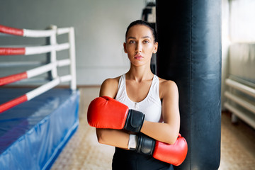 Sporty young woman wearing boxing gloves posing in gym