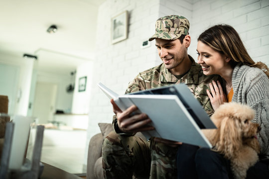 Happy military couple looking at photo album at home.