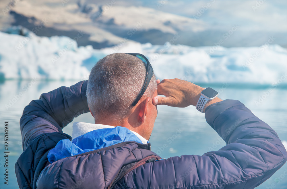 Poster Tourist looking far away visiting Jokulsarlon Glacier Lagoon in summer, Iceland