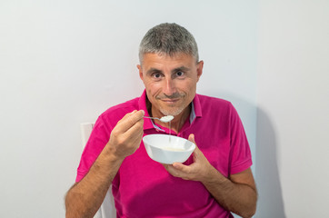 Happy man eating yoghurt from a cup