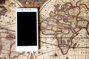white smartphone lies on a vintage world map, travel and travel theme, business tourism, a combination of vintage style and modernity