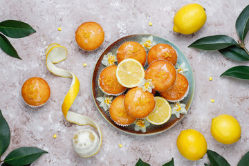 Delicious freshly baked homemade lemon muffins with lemons on a plate on light background