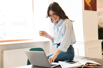 Attractive young brunette woman studying in the cafe indoors