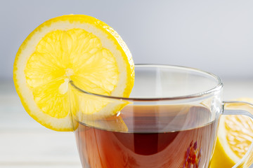 Tea in a cup with lemon on a wooden background.
