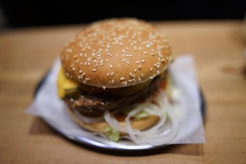 Cheeseburger with cheese, tomato, lettuce and onions on metal plate