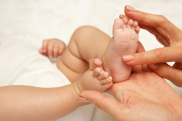 Hands of woman holds baby foot, blurred background