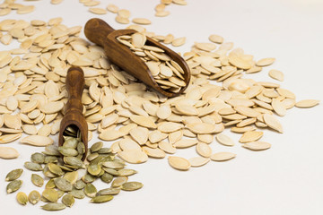 Pumpkin seeds and two wooden spoons on white background