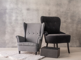 Sillon gris y sillón negro en salón con paredes de cemento