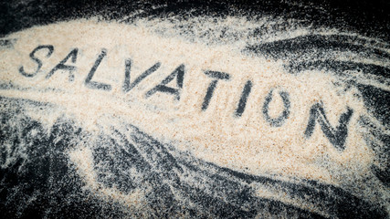 Closeup of SALVATION word written on white sand - obrazy, fototapety, plakaty