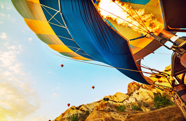 A huge balloon is inflated by fire, preparing for flight. in the background are other balloons and...