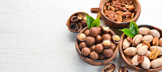 Set of nuts. pecans and macadamia nuts in bowls on a white background. Top view. Free space for your text.