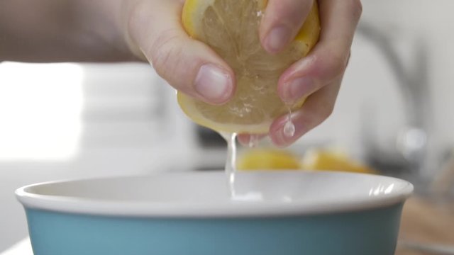 Slow motion shot as squeezing a lemon in to a bowl in the kitchen.