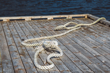 Worn out thick mooring rope on wooden pier. Can use as banner. Place for text or advertising