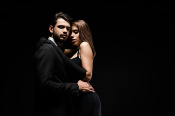 handsome man hugging beautiful woman in dress isolated on black