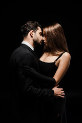 side view of handsome bearded man and woman kissing isolated on black