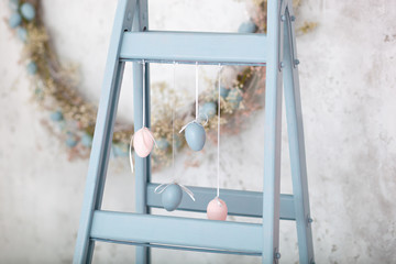 Easter holiday. Home decor blue  ladder and eggs garland background. Decorative diy wooden symbol. Decorative wooden ladder. Spring room decor. Rustic style. family celebration. Easter colorful eggs 