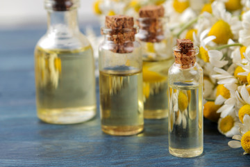 Medicinal chamomile and chamomile extract in a bottle. oil from chamomile flowers. aromatherapy. a drug. on a blue wooden table. close-up