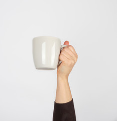 white ceramic cup in a female hand on a white background