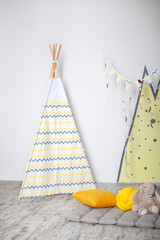 Interior of modern children's room with yellow teepee. Children wigwam home. Interior of stylish children's room with toys. scandinavian style. Kids room with a beautifully decorated play tipi tent. © stock_studio