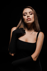 attractive woman with closed eyes in gloves isolated on black