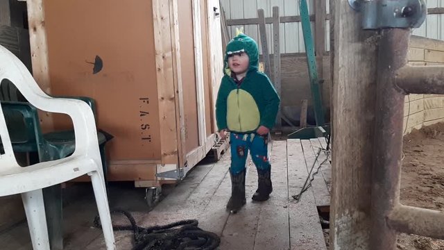 Child in Dinosaur Costume Jumping in wood barn