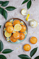 Delicious freshly baked homemade lemon muffins with lemons on a plate on light background