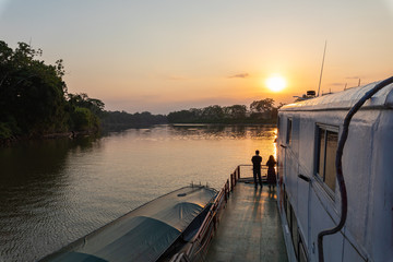 Amazon rainforest sunset during a boat trip with a reflection of the trees in the water. Puerto...