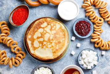 Shrovetide Maslenitsa festival meal. Russian pancake blini with raspberry jam, honey, fresh cream and red caviar,sugar cubes,cottage cheese,bubliks on light background