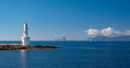 White lighthouse in La Savina, Formentera island, with the island of Ibiza in the background, Spain