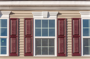 White soffit providing optimal ventilation for roof overhangs. Double pane window framed with a narrow lineal trim terracotta shutters, crown molding accent, light maple vinyl horizontal sliding